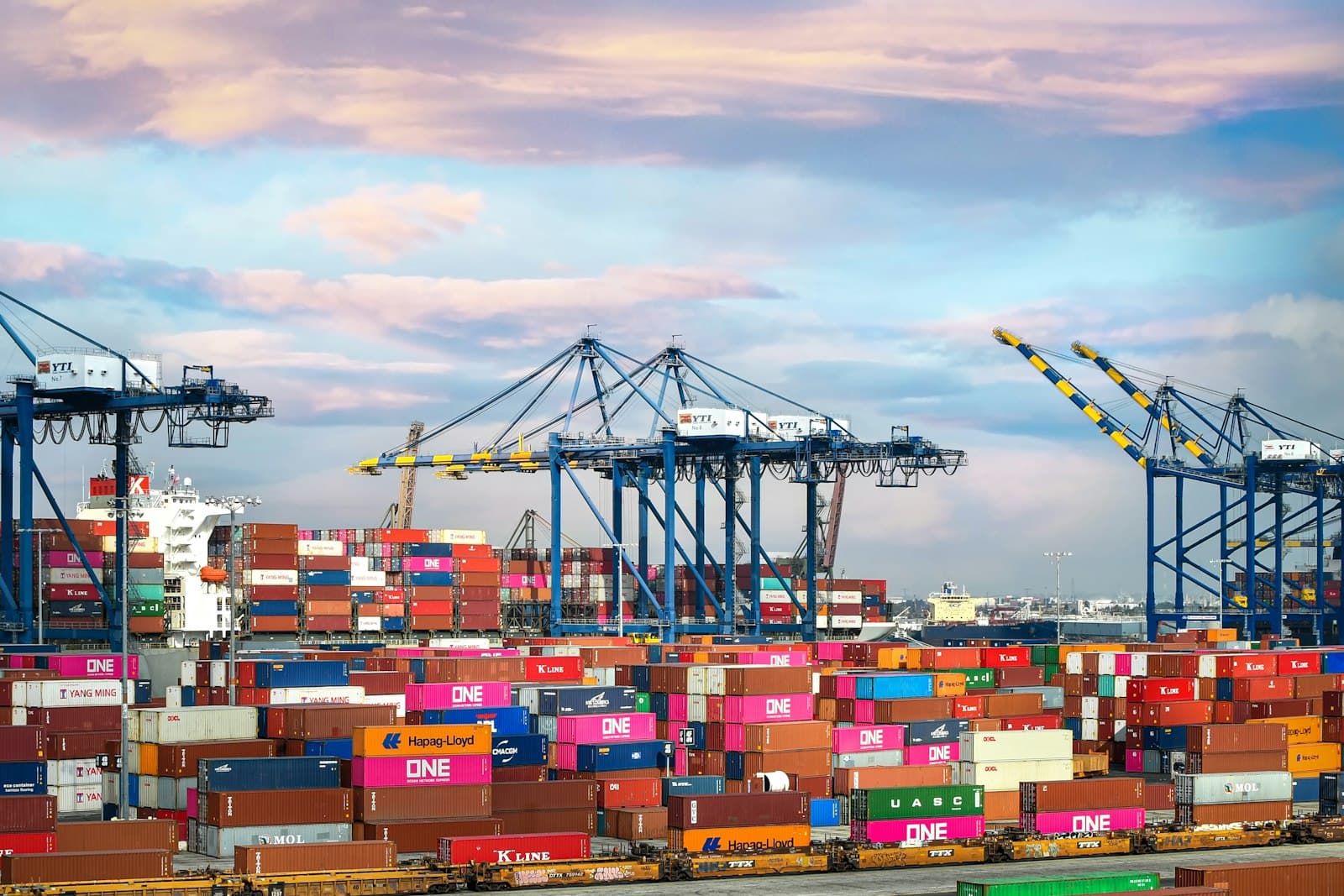 Stacked shipping containers and cranes at a busy port