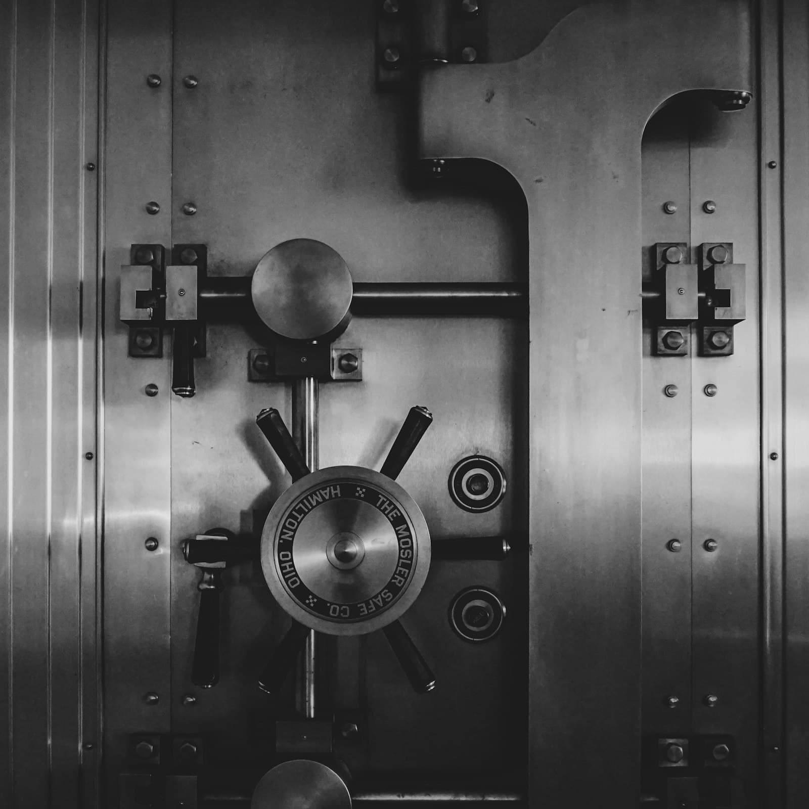 A heavy steel bank vault door with a large circular locking wheel